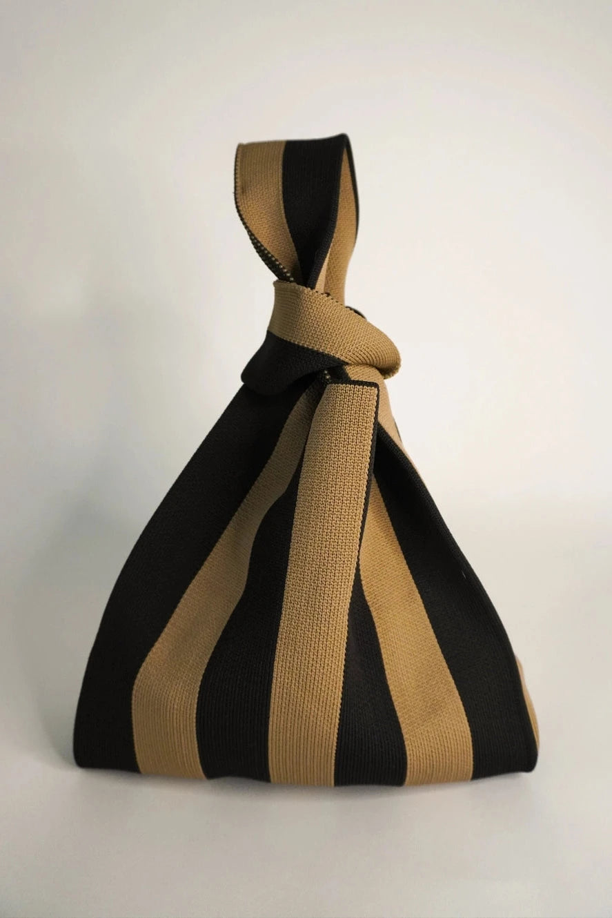 Black and beige striped bag with a knot on a white background