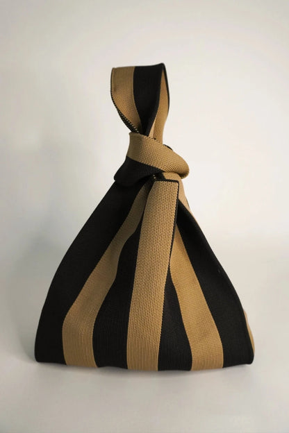 Black and beige striped bag with a knot on a white background