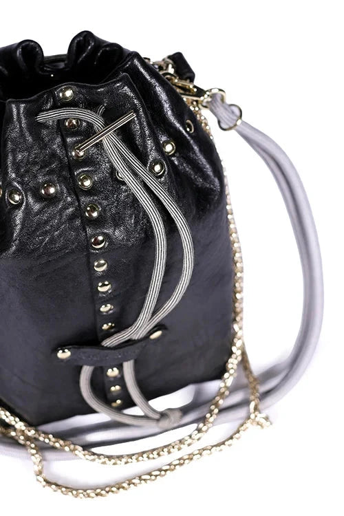 Black drawstring bag with gold studs and a white strap on a white background