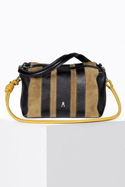 A small structured handbag with vertical black and tan stripes, black leather trim, a black top handle, and a bright yellow shoulder strap, displayed on a white pedestal against a white background.