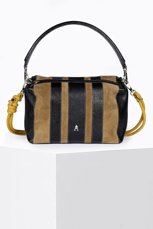 A structured leather shoulder bag with vertical stripes in black and tan suede, displayed on a white pedestal. The bag features a black leather top handle, a matching black leather shoulder strap, a yellow-gold knotted detail on the side, and a small silver 'A' logo on the front.