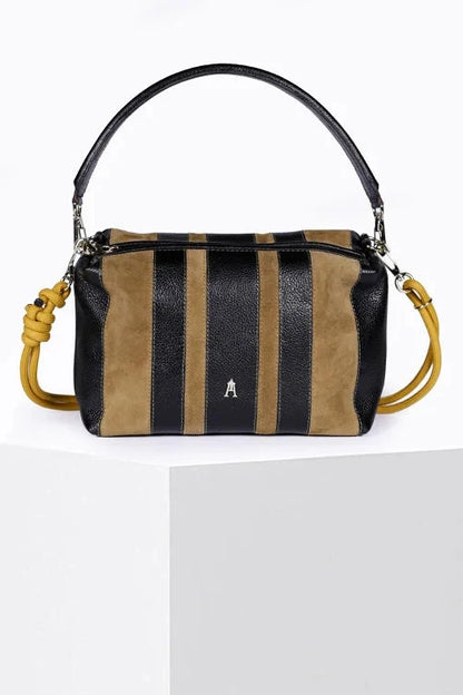 A structured leather shoulder bag with vertical stripes in black and tan suede, displayed on a white pedestal. The bag features a black leather top handle, a matching black leather shoulder strap, a yellow-gold knotted detail on the side, and a small silver 'A' logo on the front.