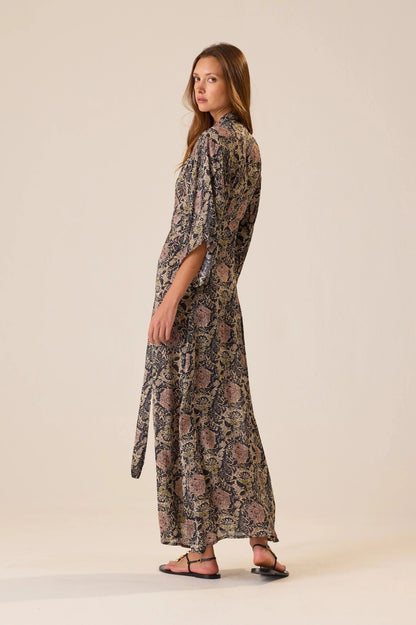 Woman wearing a long, patterned dress on a beige background