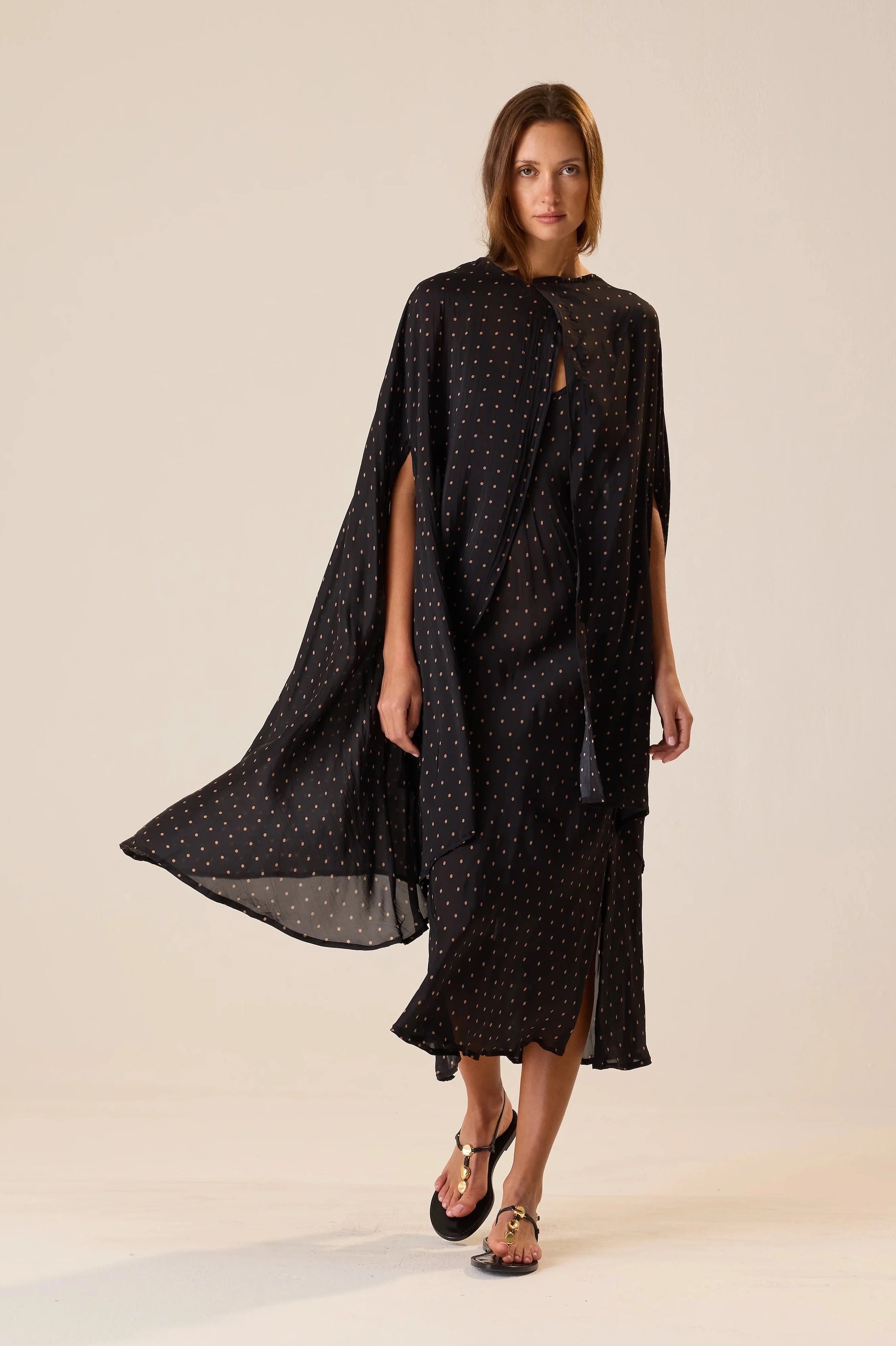 Woman wearing a black patterned dress against a beige background