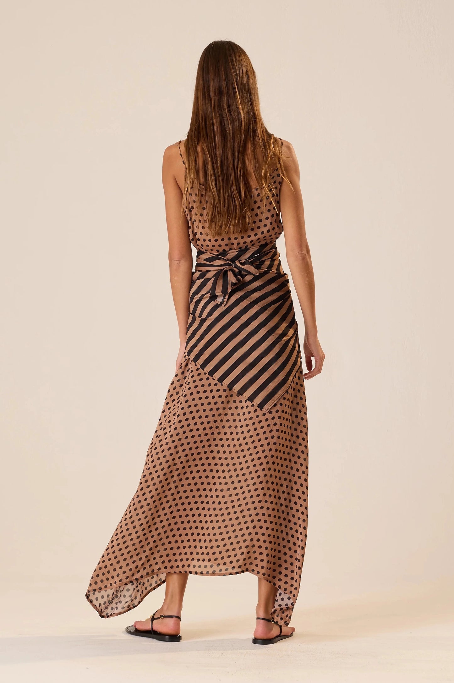Woman wearing a patterned dress with a bow detail on a beige background